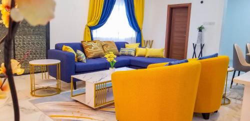 a living room with a blue couch and yellow chairs at RS Royal Executive Luxurious 3BR Apartment F3-3 and 2BR Apartment F3-2 in Pantang