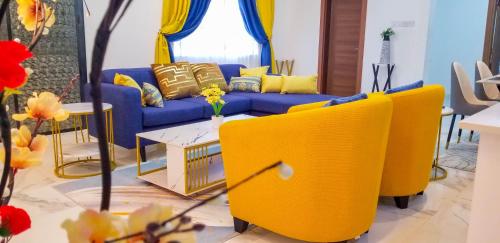 a living room with a blue couch and yellow chairs at RS Royal Executive Luxurious 3BR Apartment F3-3 and 2BR Apartment F3-2 in Pantang