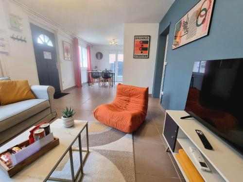 a living room with an orange couch and a tv at Le Central - Rez de jardin in Liévin