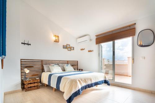 a white bedroom with a bed and a large window at Chalet adosado en la playa de Torre de la Horadada in Torre de la Horadada