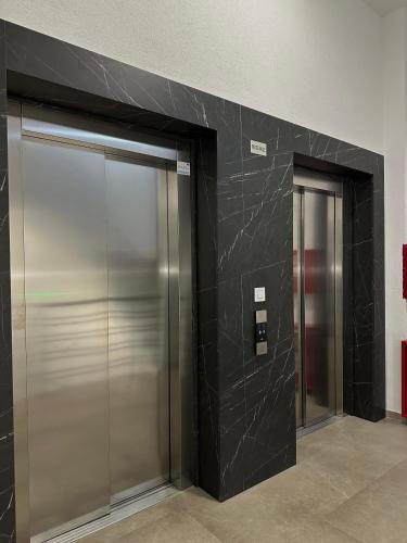 due porte dell'ascensore in un edificio con pareti nere di Tre Sorelle a Podgorica