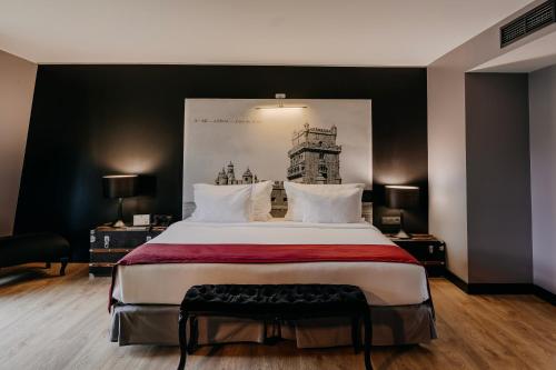 a bedroom with a large bed with a painting on the wall at 138 Liberdade Hotel in Lisbon