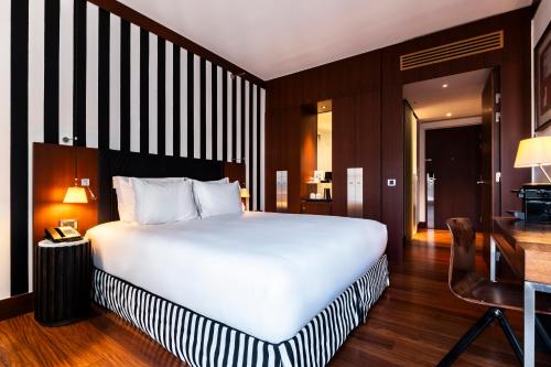 a bedroom with a large white bed and a desk at Grand Hôtel Champs-Elysées in Paris