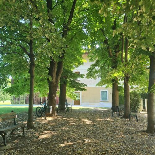 a park with benches and trees with a building in the background at Dimora all'Angolo - moderno e in centro in Affi