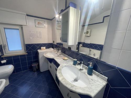 a blue tiled bathroom with two sinks and a toilet at Bed & Breakfast L'Albero Maestro in Borgofranco dʼIvrea