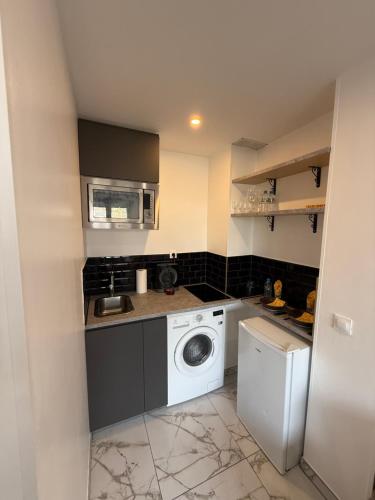 a small kitchen with a washing machine and a washer at CHARMANTE STUDIO PROCHE PARIs in Choisy-le-Roi