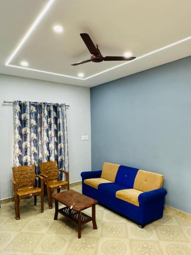 a living room with a blue couch and chairs at Sw by The Saltwater Homestay in Udupi