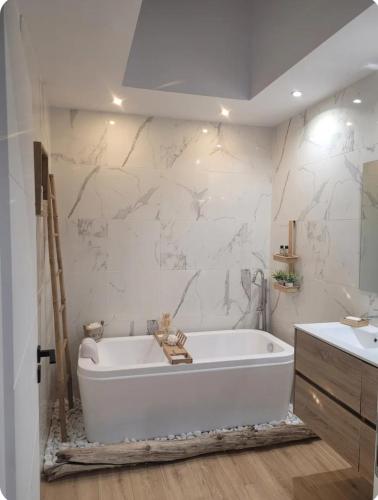 La salle de bains est pourvue d'une baignoire blanche et d'un mur en marbre. dans l'établissement Magnifique Villa piscine jacuzzi privé, à Saint-Féliu-dʼAvall