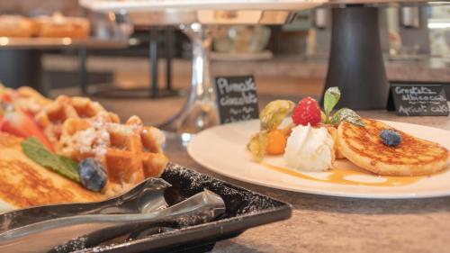 a plate of food with waffles and fruit on a table at Paradise Lodge in Livigno