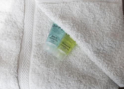 una botella de crema hidratante sentada en una manta blanca en MARINA HOTEL London, en Londres