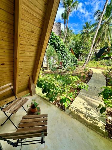 a wooden porch with a bench and palm trees at Leisy's Garden Hostel & Rooms in Santa Bárbara de Samaná