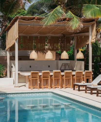 a pool with chairs and a table and a pavilion at Tankah Bay 56 in Balcheil