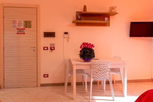 a white table with chairs and a vase of flowers on it at Appartamenti DueC in Trapani