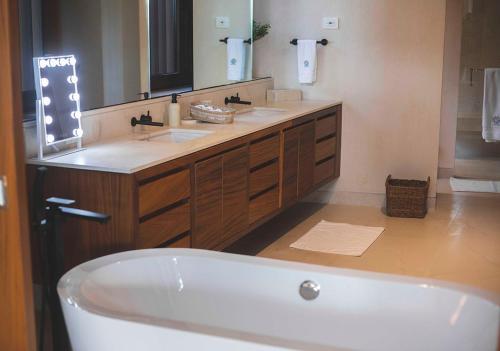 a bathroom with a tub and two sinks and a mirror at Casa Coral, Luxury Beachfront in Higuera Blanca