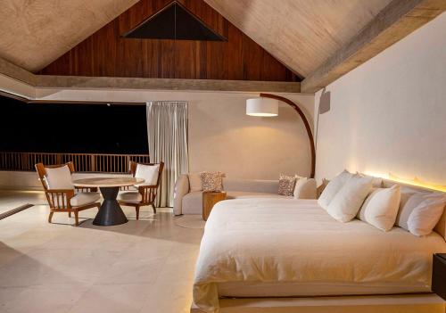 a bedroom with a bed and a table with chairs at Casa Coral, Luxury Beachfront in Higuera Blanca