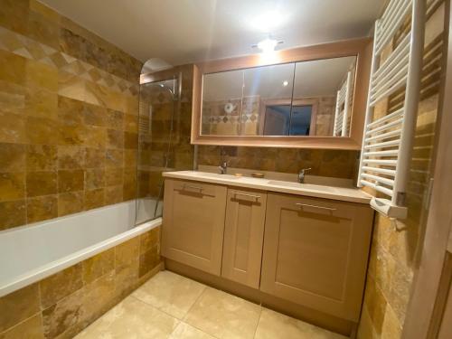 une salle de bain avec un lavabo, un miroir et une baignoire dans l'établissement domaine de la baie, à Cavalaire-sur-Mer