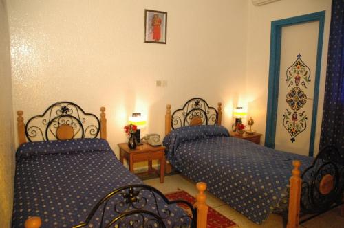 a bedroom with two beds with blue comforter at Hotel Tiout in Taroudant