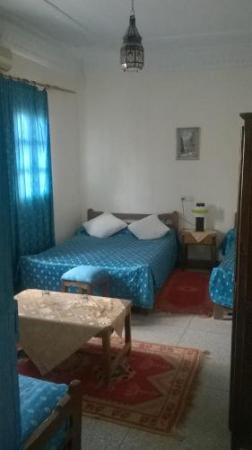 a bedroom with two beds and a table in it at Hotel Tiout in Taroudant