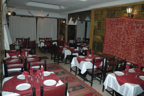 une salle à manger avec des tables et des chaises ainsi que des tables et des chaises rouges dans l'établissement Hotel Tiout, à Taroudant