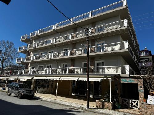 a building with balconies and a truck parked in front of it at Apartments Villa Effie in Paralia Katerinis