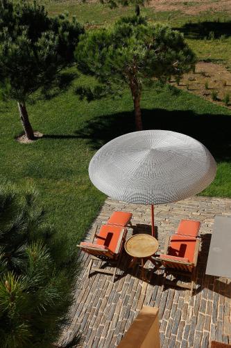 a table and chairs with a table and an umbrella at Praia do Canal Nature Retreat - Small Luxury Hotels of the World in Aljezur