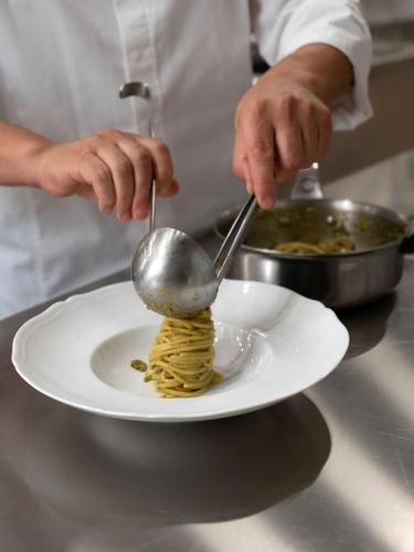 a chef preparing pasta on a plate with a spoon at Palazzo Talìa - Small Luxury Hotels of the World in Rome