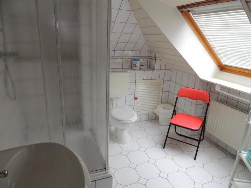 ein Badezimmer mit einem WC und einem roten Stuhl in der Unterkunft Ferienwohnung Karin in Schneverdingen