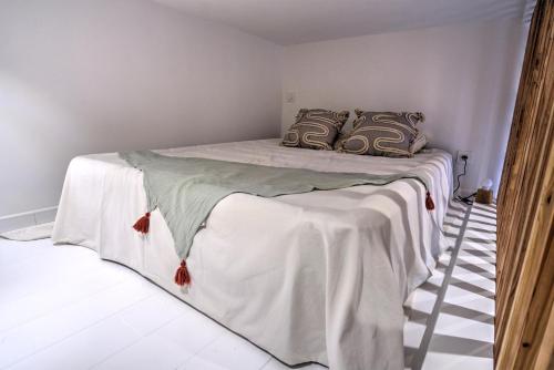 une chambre avec un lit avec des draps blancs et des oreillers dans l'établissement Petit cocon en cœur de ville, à Arcachon