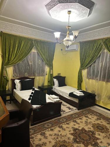 a bedroom with two beds and a chandelier at Riad Dar Fadma in Ouarzazate