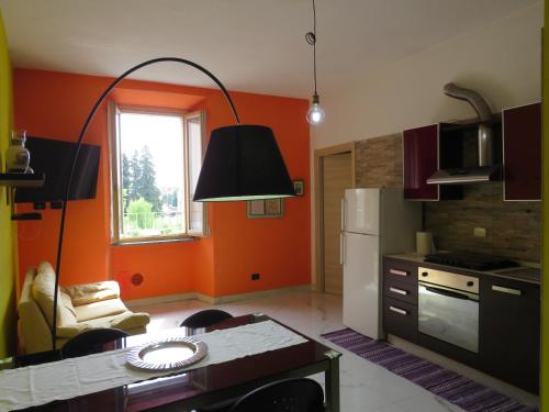 a kitchen with orange walls and a table and a refrigerator at Appartamento tra Milano e Como in Caronno Pertusella