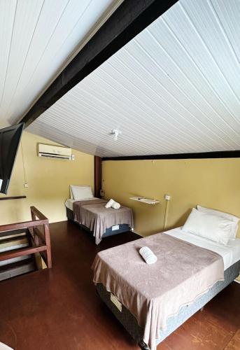 a room with two beds and a flat screen tv at Pousada Aventurine Noronha in Fernando de Noronha