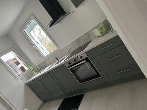 d'une cuisine avec des placards gris, un évier et une fenêtre. dans l'établissement Au champ du bourg, à Bourbon-Lancy