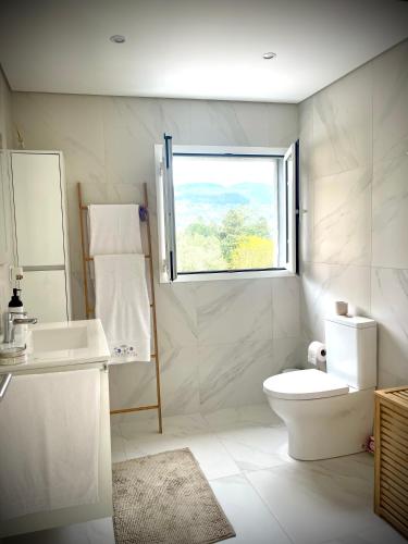 a white bathroom with a toilet and a window at Casa da nascente douro in Paços de Gaiolo