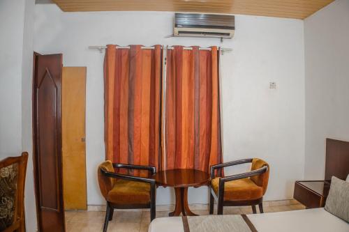 a room with a table and two chairs and a curtain at Stadium Hotel in Kumasi