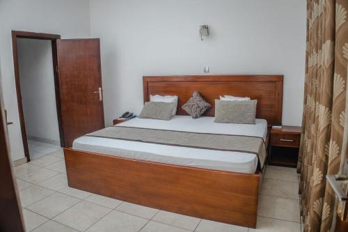 a bedroom with a bed with a wooden headboard at Stadium Hotel in Kumasi