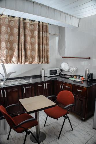 a kitchen with two chairs and a table in it at Stadium Hotel in Kumasi
