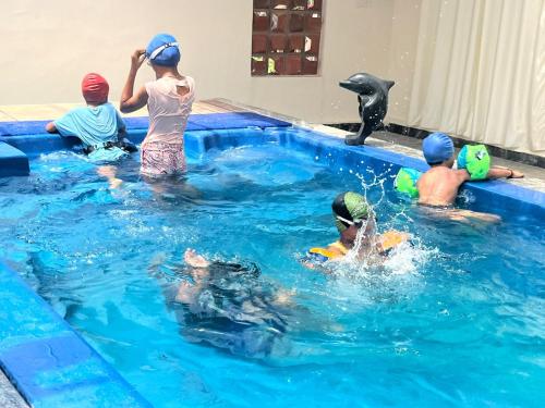 a group of children in a swimming pool with a dolphin at Jacob Farms in Denkanikottai