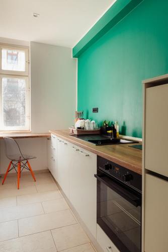 a kitchen with white cabinets and a blue wall at Heart of Old Town in Bucharest