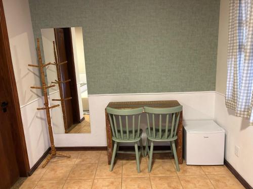 a kitchen with a table and two green chairs at Pousada Flor de Lua Monte Verde in Monte Verde