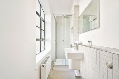 a white bathroom with a sink and a shower at Farringdon Comfortable 3 Bed Apartments in London