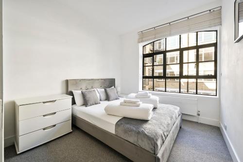 a white bedroom with a large bed and a window at Farringdon Comfortable 3 Bed Apartments in London