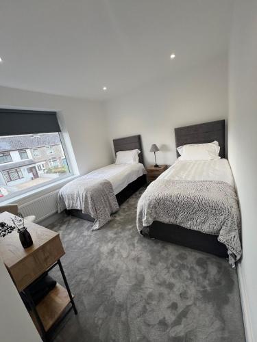 a white room with two beds and a window at Luxury Modern 3 Bedroom House in Bridgend