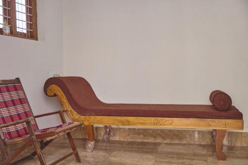 a wooden bench sitting against a wall next to a chair at Jacob Farms in Denkanikottai