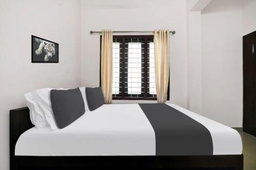 a black and white bed in a room with a window at Hotel O GRAND RESIDENCY in Ambalapulai