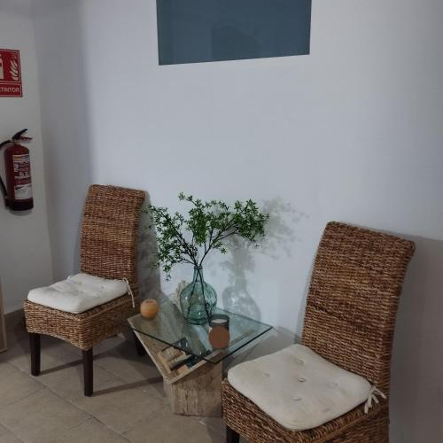 two wicker chairs and a glass table with a plant at La Milotxa in Adsubia