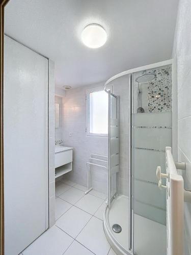 une salle de bain blanche avec une douche et un lavabo dans l'établissement Bel appartement vue mer-montagne, à Calvi