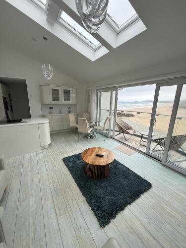 a living room with a table in the middle at Stylish beachfront penthouse in Perranporth
