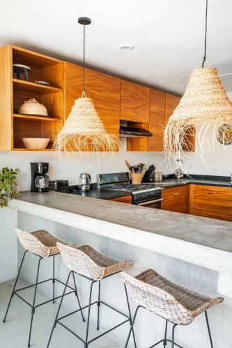 a kitchen with two bar stools and wooden cabinets at Casa Lulú, Oasis with Pool and Panoramic Terrace in San José del Cabo