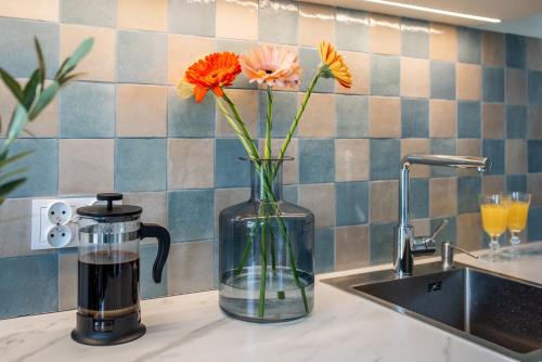 un jarrón lleno de flores en un mostrador junto a un fregadero en Wawel View Stylish Apartment - Kościuszki 22, en Cracovia