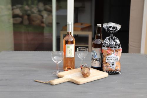 a table with two wine bottles and two wine glasses at Un cocon de détente entre mer et nature in Zonza